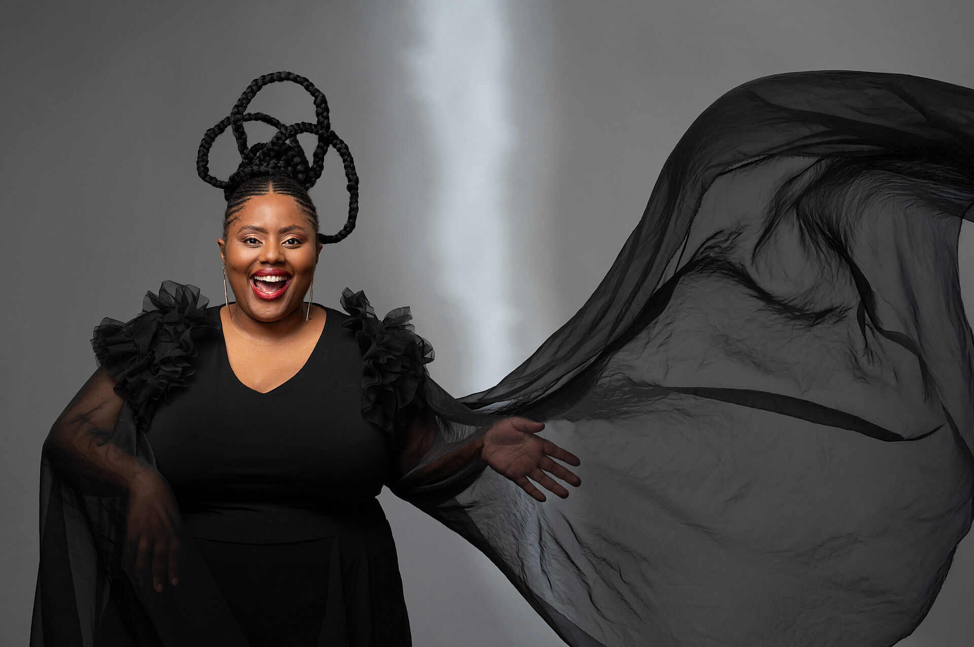 Expressive woman from South Africa in a black dress with a flowing scarf.