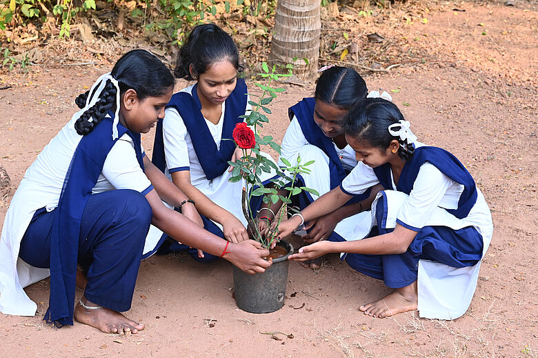 Indian girls gather around a flower