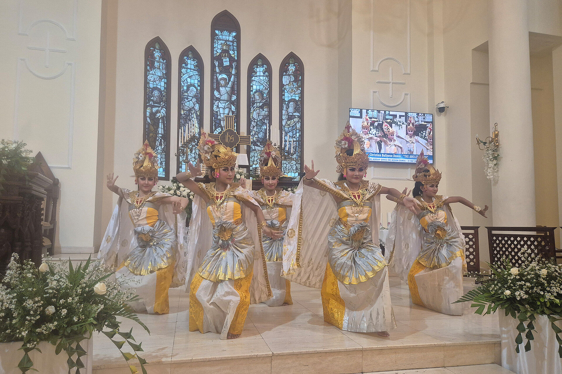 Balinese women performing a dance in a church wearing traditional costumes.