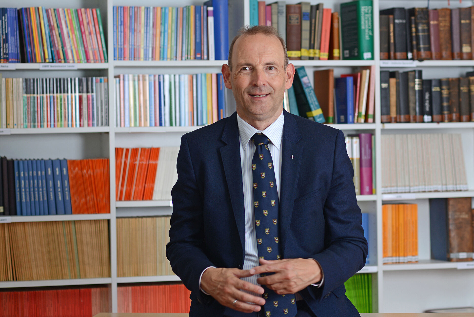 Generalsekretär der EMS, Dr. Dieter Heidtmann, vor einer Bücherwand sitzend.