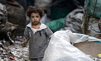 Junge in Kairo zwischen Müllsäcken.