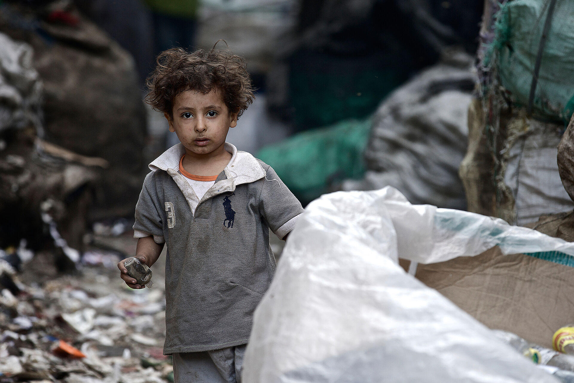 Junge in Kairo zwischen Müllsäcken.