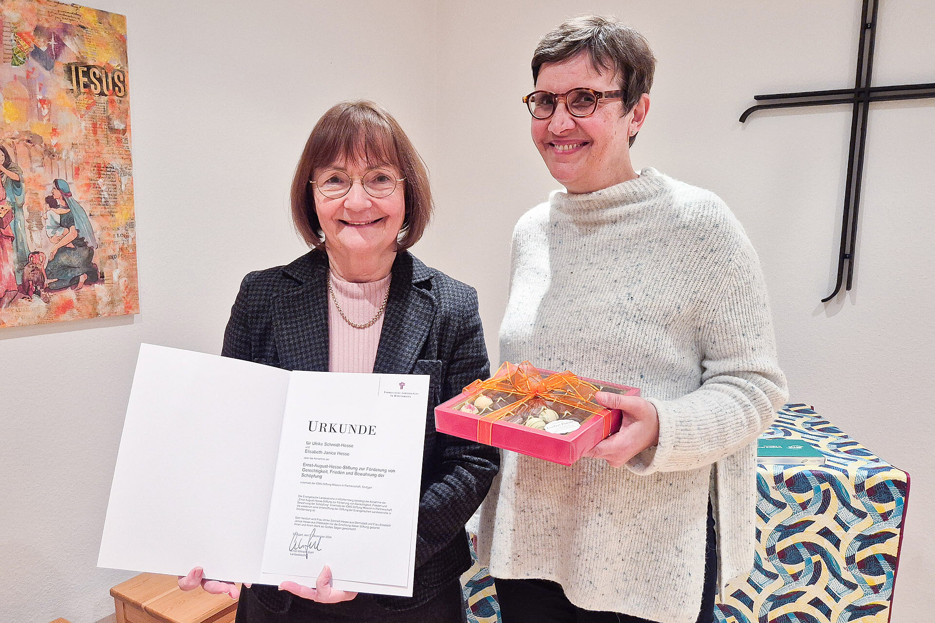 Two women stand next to each other and hold a certificate in their hands