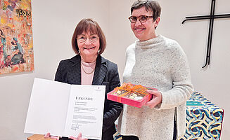 Two women stand next to each other and hold a certificate in their hands